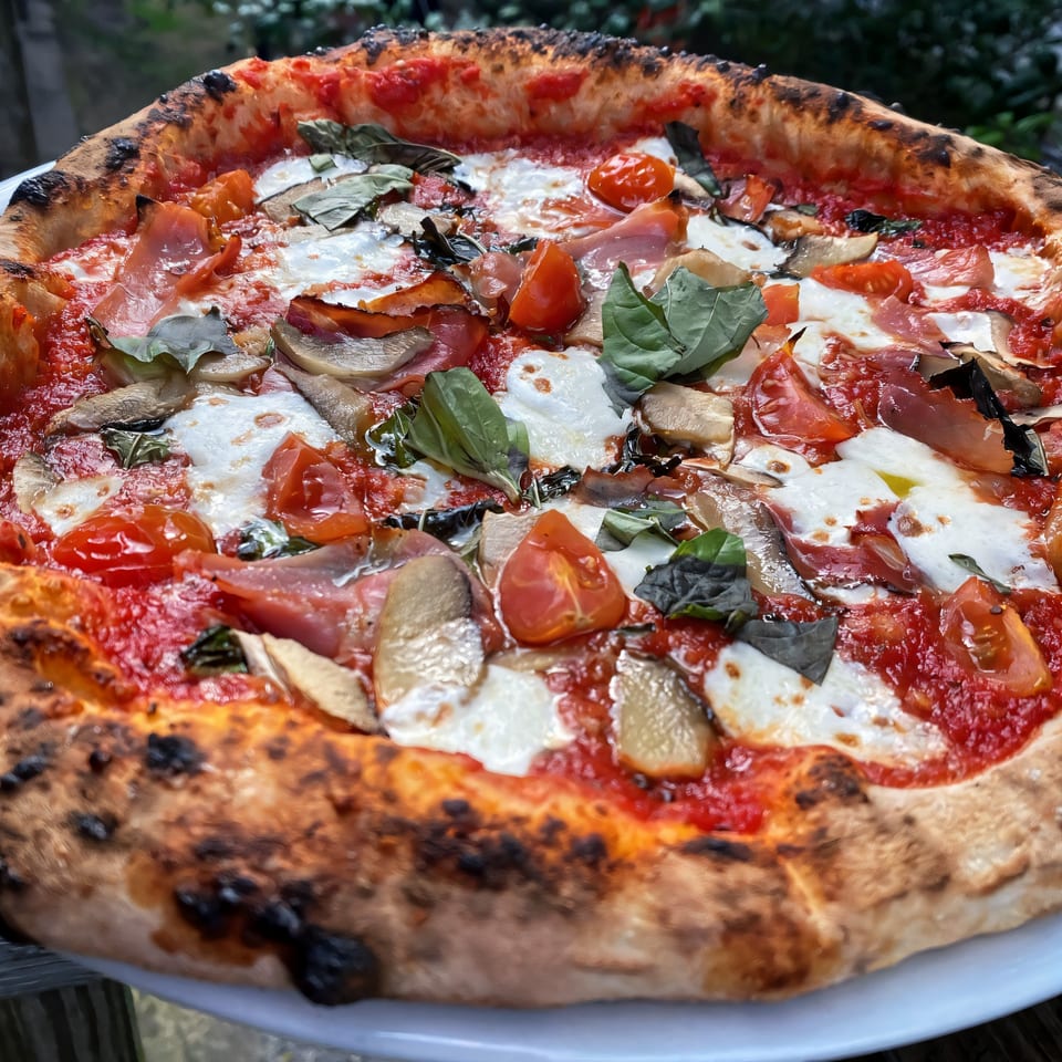 Aquila Pizza Al Forno's pizza with prosciutto, mushrooms, cherry tomatoes, mozzarella, and basil.