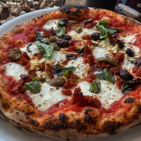 Aquila Pizza Al Forno's wood-fired pizza with tomato sauce, mozzarella, basil, olives, and sausage.