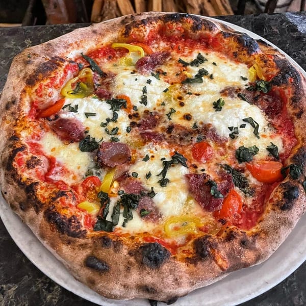 Aquila Pizza Al Forno's wood-fired pizza with pepperoni, mozzarella, tomatoes, peppers, and basil.
