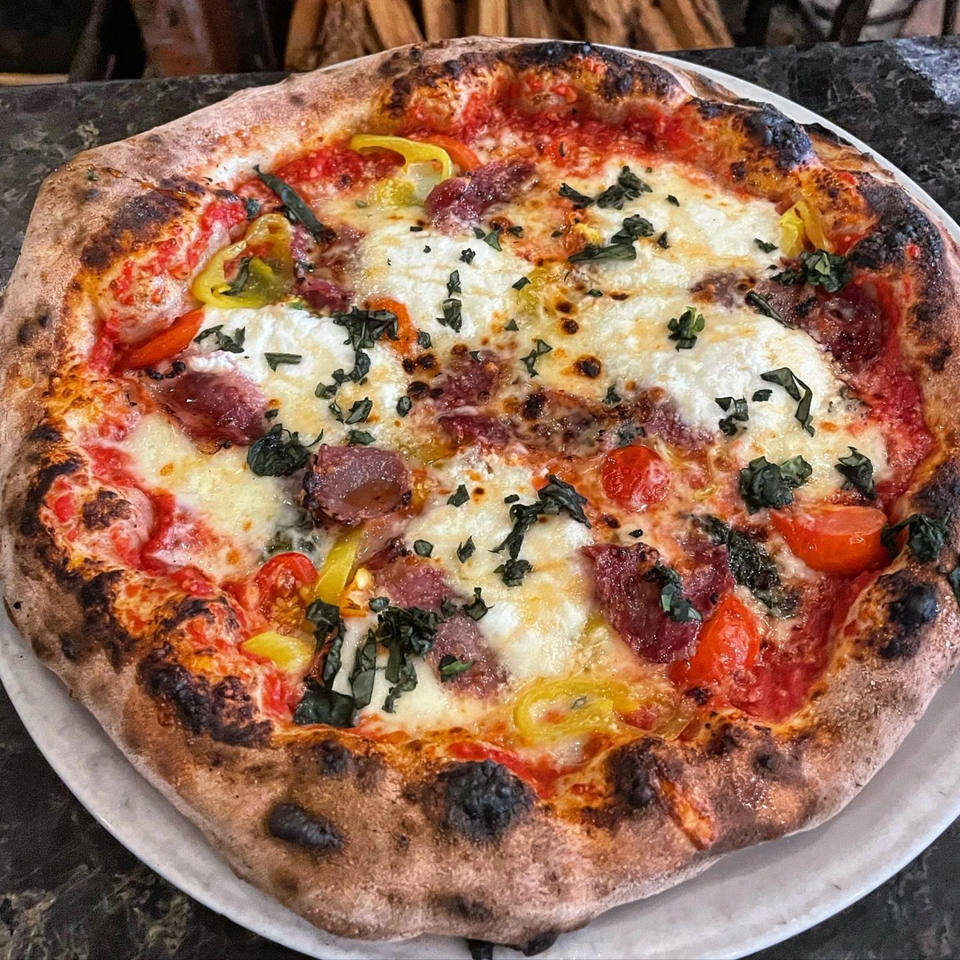 Aquila Pizza Al Forno's wood-fired pizza with pepperoni, mozzarella, tomatoes, peppers, and basil.