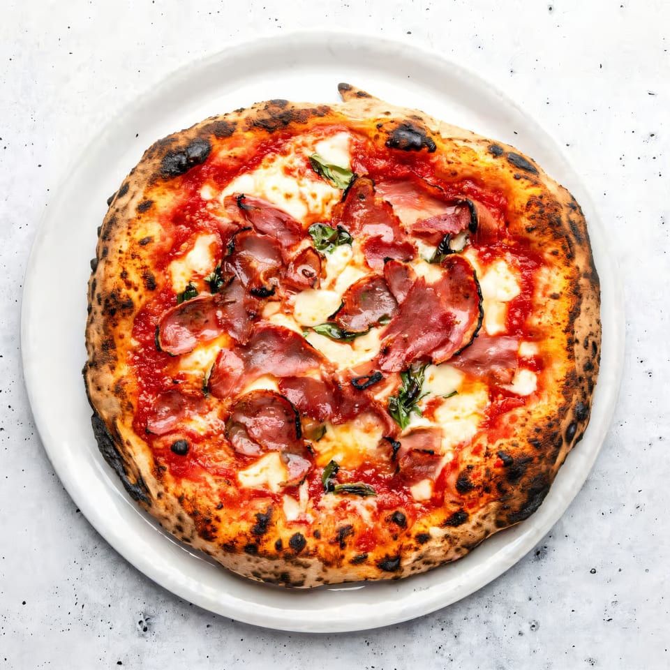 Aquila Pizza Al Forno's pepperoni pizza with melted cheese and basil on a white plate.